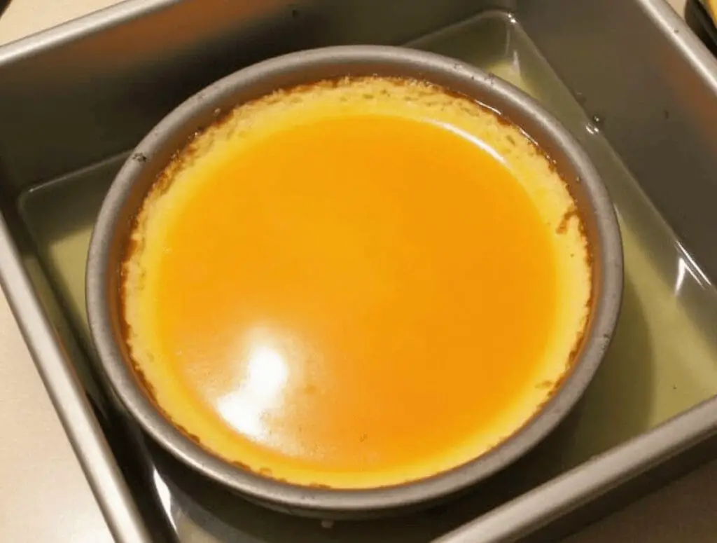 Flan de queso colocado en un molde con caramelo, listo para cocinarse en baño maría en el horno.