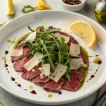 Carpaccio de ternera gourmet servido con rúcula fresca, parmesano en lascas y aliño clásico.
